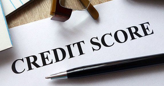 Paper with Credit Score text, pen, and paperclip on a desk, representing financial evaluation and reporting.