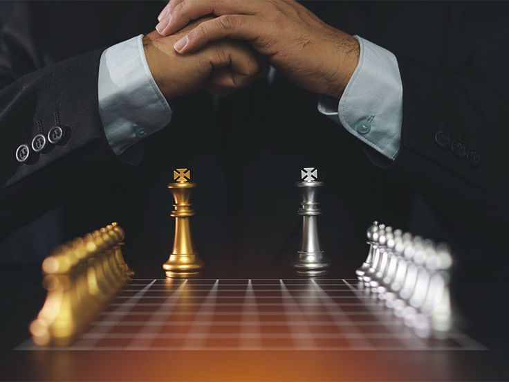 Man strategizing over a chessboard with gold and silver pieces, symbolizing leadership and decision-making in business.