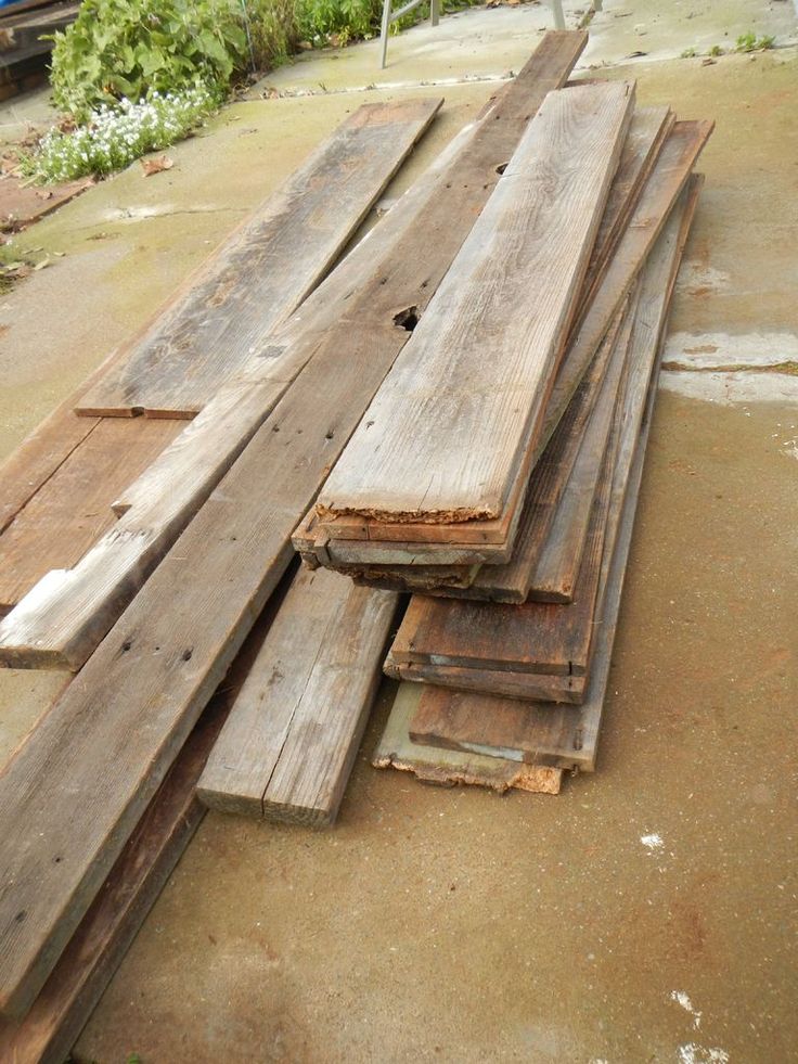 Stack of reclaimed wood planks on concrete, ideal for DIY projects and sustainable home improvement.