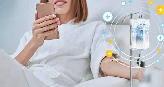 Woman relaxing with phone during IV therapy session, highlighting wellness and hydration benefits.