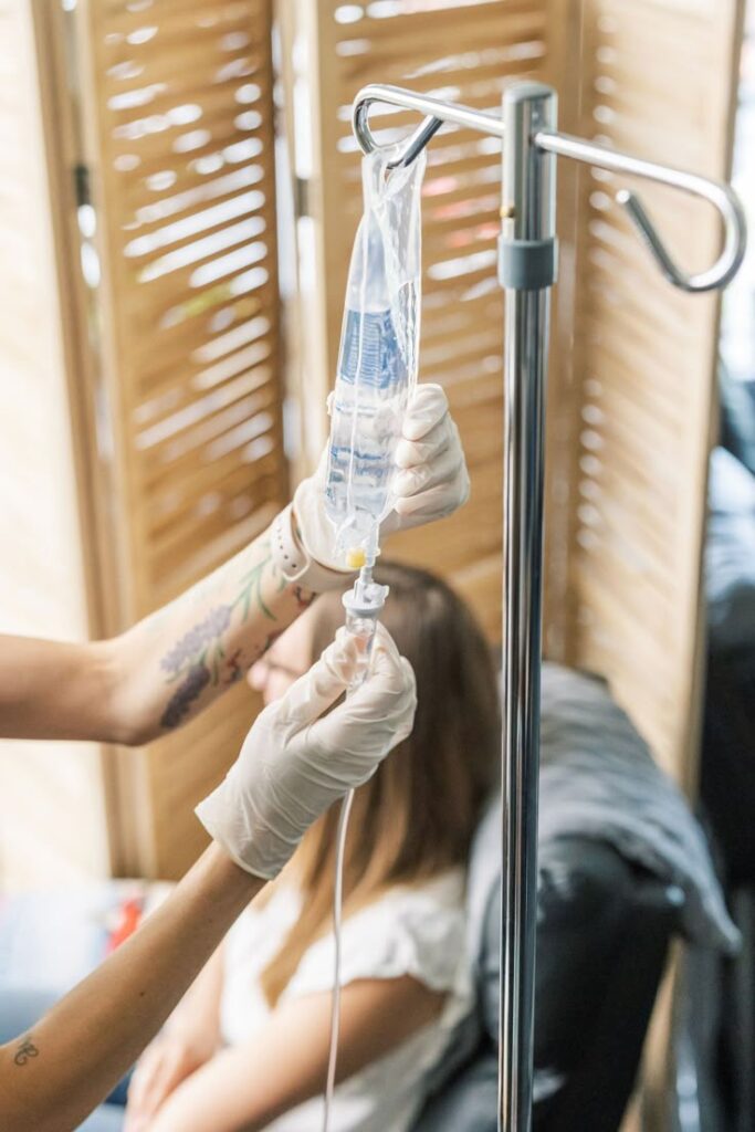 Healthcare professional preparing IV drip for patient in clinical setting.