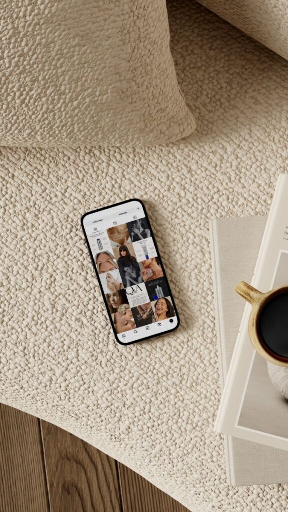 Smartphone displaying Instagram photos on a beige textured bedspread with a coffee cup and book nearby.