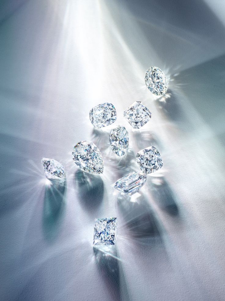 Sparkling diamonds with various cuts reflecting light on a soft surface.