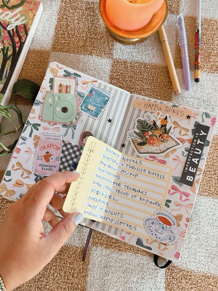 Decorative journal page with hand holding a list titled Happy Things, surrounded by stickers and a lit candle.