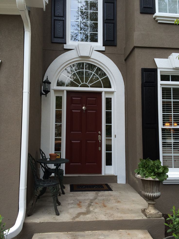 LOVE my front door My favorite color pick SW 2802 Rookwood Red Front porch with a red door, arched window, black shutters, and small seating area with potted plant. | Sky Rye Design Front porch with a red door, arched window, black shutters, and small seating area with potted plant.