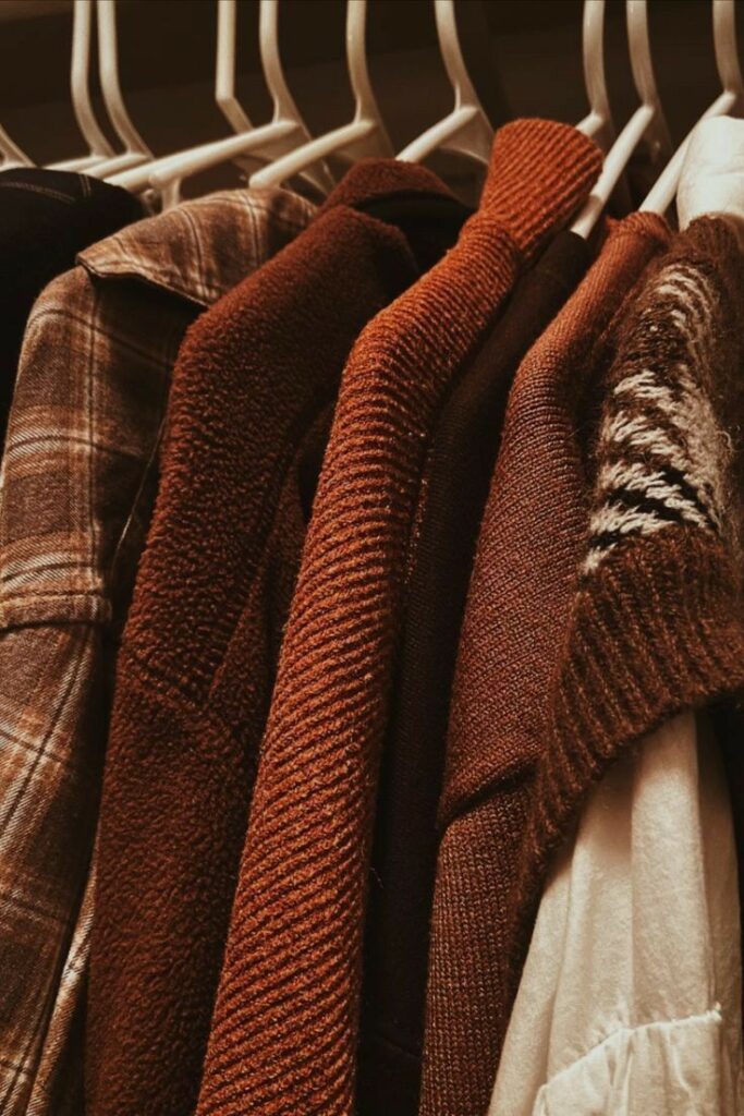 Close-up of brown and plaid winter coats hanging in a wardrobe on white hangers. Cozy and stylish outerwear collection.