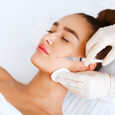 Person receiving a cosmetic injection on the cheek at a beauty clinic, enhancing facial appearance.