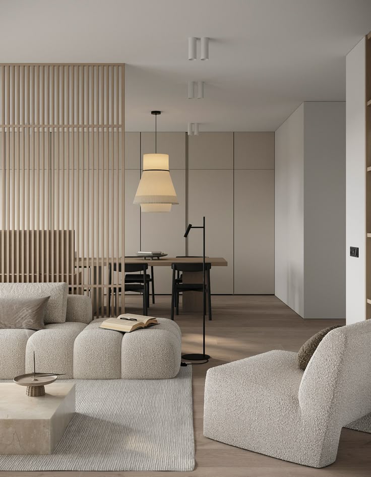 Modern living room with beige furniture, wooden partition, and minimalist decor; open book on plush sofa.