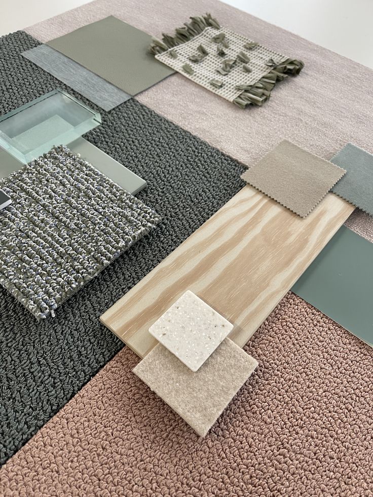 Interior design material samples arranged on a surface, showcasing fabrics, wood, and textures in neutral tones.
