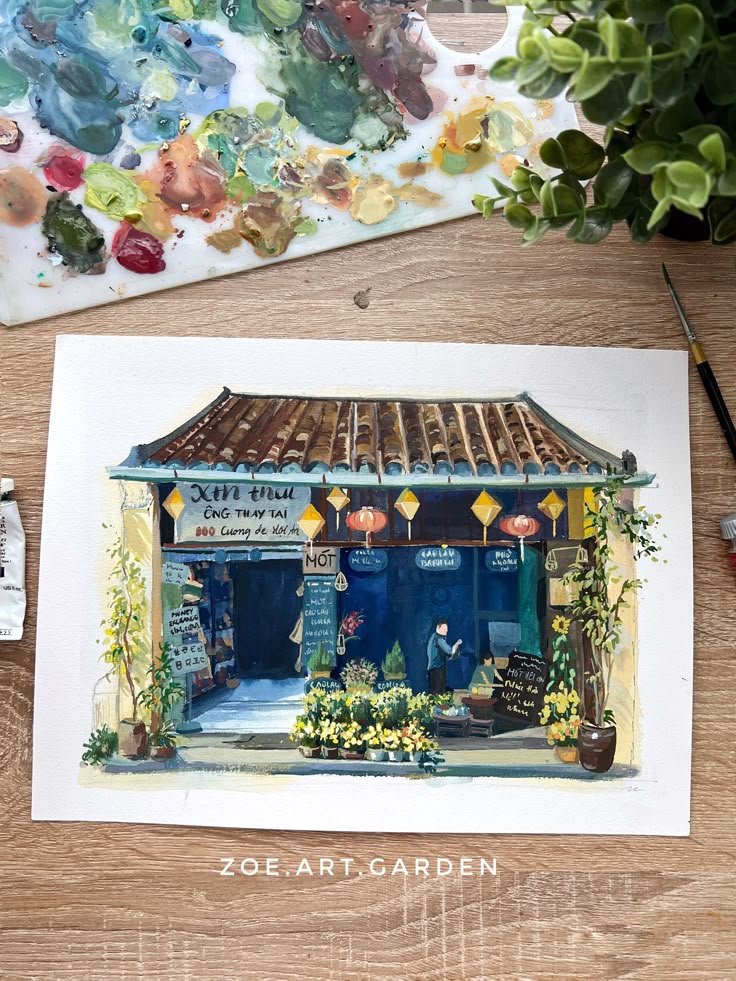 Watercolor painting of a charming shop with plants and colorful lanterns, captured on a wooden table with artist tools.