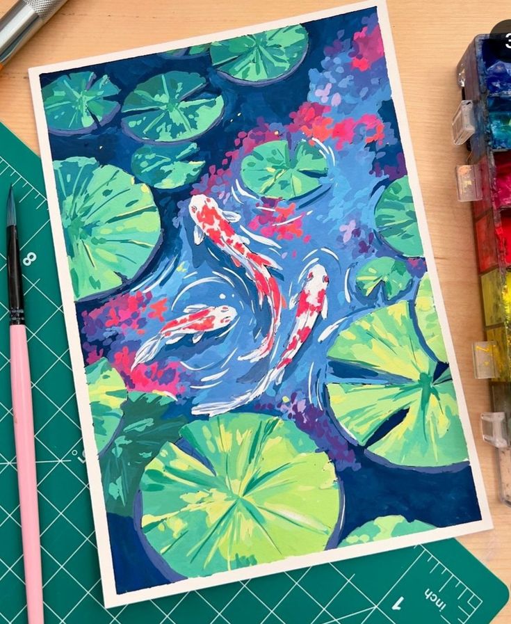 Colorful koi fish swimming among lily pads in a pond painting, with artistic tools nearby.