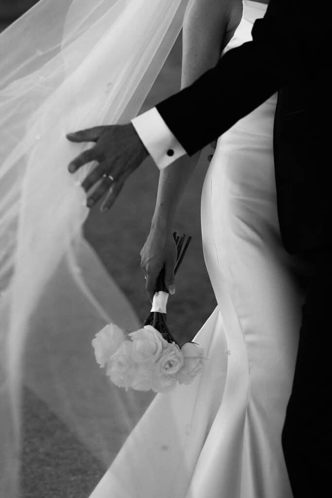 Pasalic Studio Bride holding bouquet, veil flowing, elegant wedding dress, intimate moment. | Sky Rye Design Bride holding bouquet, veil flowing, elegant wedding dress, intimate moment.