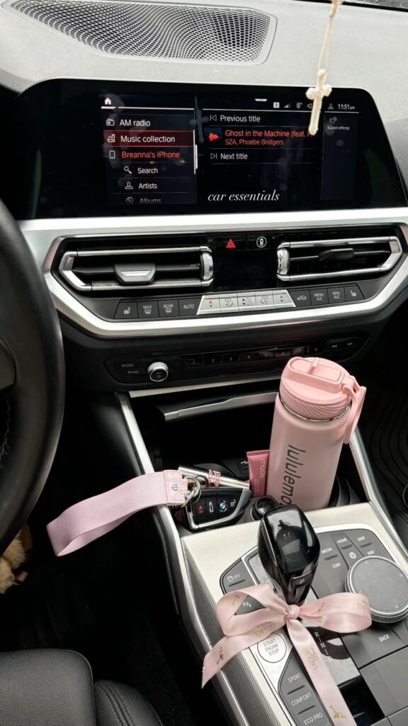 Car interior with touch screen display, pink water bottle, and keychain on console. Car essentials in a modern vehicle.