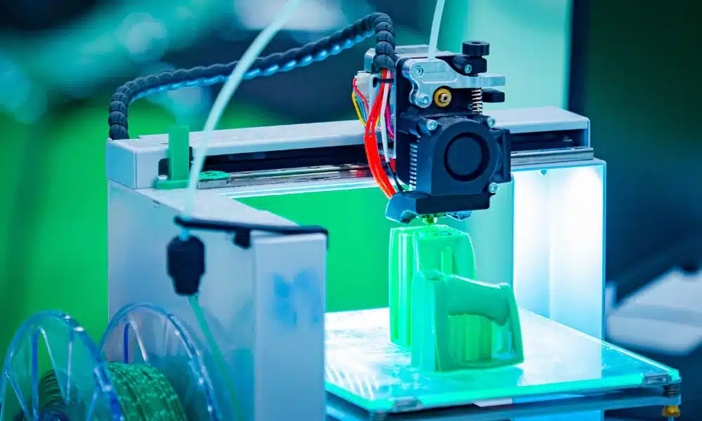 3D printer creating a green object, showcasing additive manufacturing technology in action.