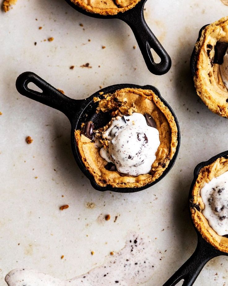 Mini skillet cookie topped with vanilla ice cream on a marbled surface. Delicious dessert close-up.