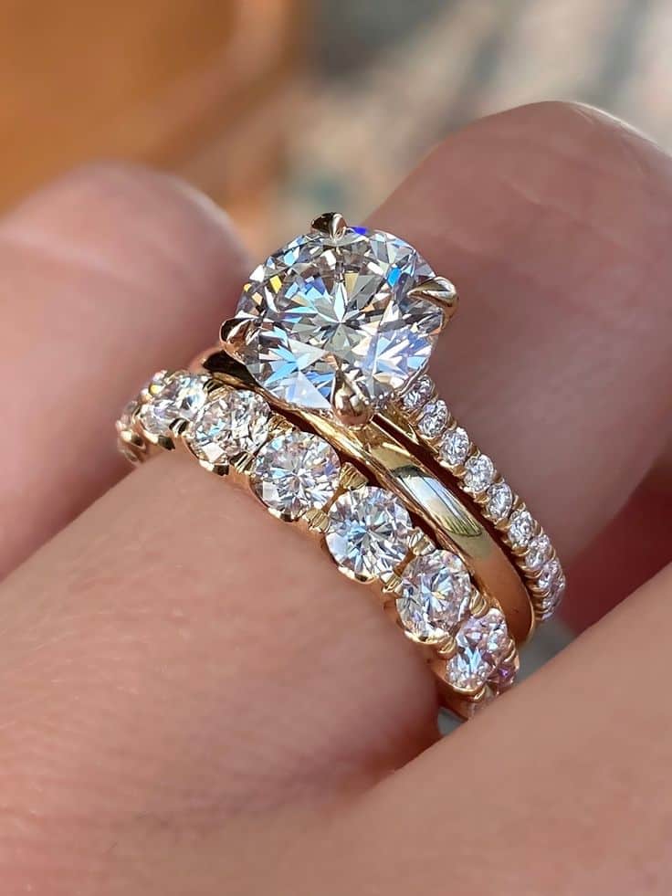 Gold diamond engagement and wedding ring set sparkling on a finger, showcasing elegant jewelry design.