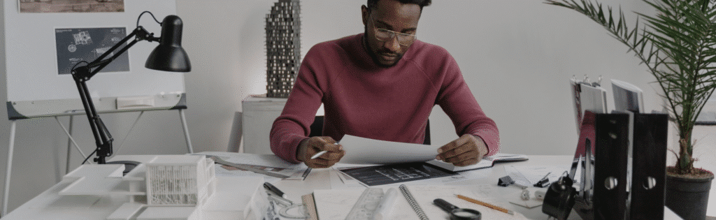 Architect reviewing blueprints in an office with design tools and drafts nearby.