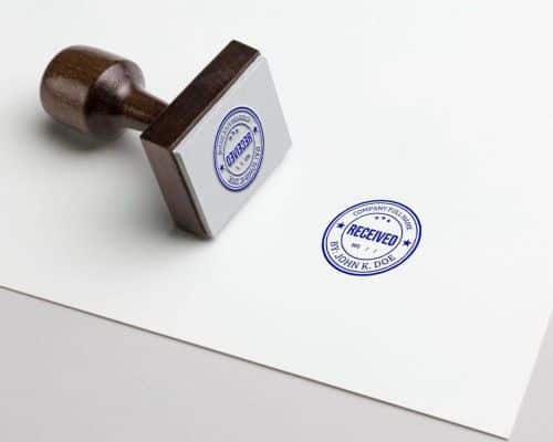 Wooden stamp marked 'RECEIVED' on paper, symbolizing document processing or official approval.