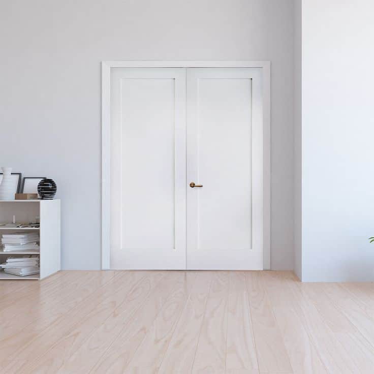 White double doors in minimalist room with light wood flooring and shelf with decor items.