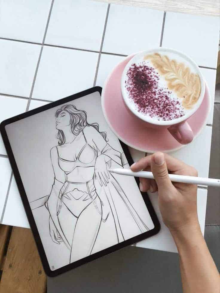 Digital sketching on tablet next to artistic coffee in pink cup, enhances creativity and relaxation.
