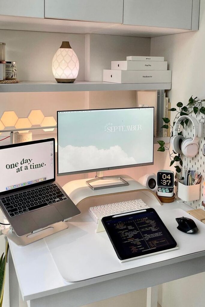 Modern home office setup with laptop, monitor, tablet, and decor. Cozy workspace featuring motivational quotes.