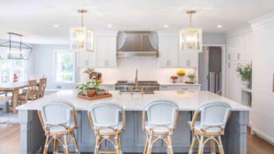 Modern kitchen with white cabinets, large island, wicker bar stools, and stylish pendant lights.