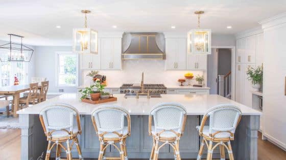 Simple Ways to Improve Kitchen Ventilation Modern kitchen with white cabinets, large island, wicker bar stools, and stylish pendant lights. | Sky Rye Design Modern kitchen with white cabinets, large island, wicker bar stools, and stylish pendant lights.