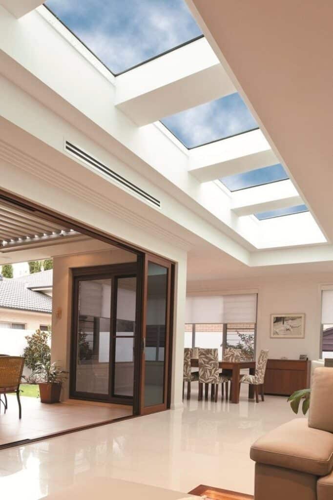 Modern open-plan living room with skylights, glass doors, and elegant dining area for natural light and spacious feel.