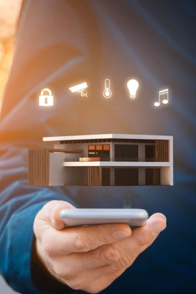 Smart home technology concept, hand holding smartphone with digital icons for security, lighting, temperature, and audio.