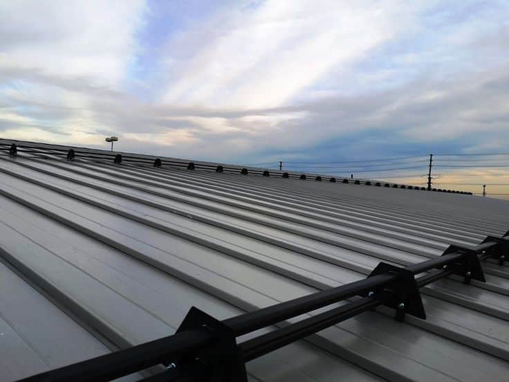 Modern metal roof with sky background, showcasing durability and sleek design against a blue and cloudy sky.