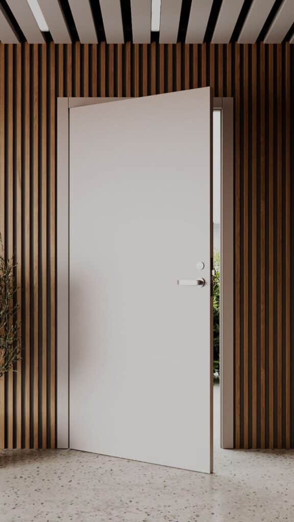 Modern white door with handle, partially open, against stylish wooden slat wall in a contemporary interior.