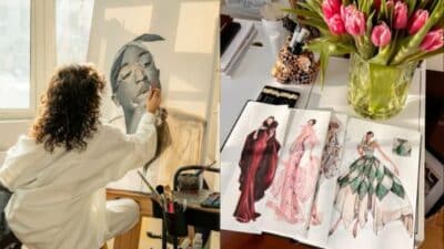 Artist painting a portrait next to fashion sketches and pink tulips on a desk, highlighting creativity and design.