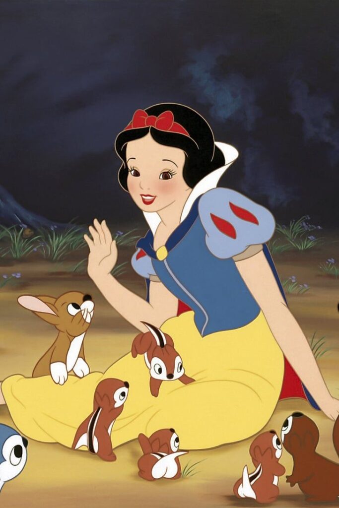 Animated princess with woodland animals, wearing a blue and yellow dress, smiles and interacts in a forest setting.