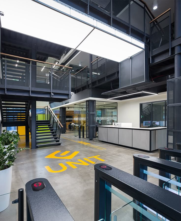 Modern office entrance with turnstiles, open layout, industrial design, and branding on the floor.