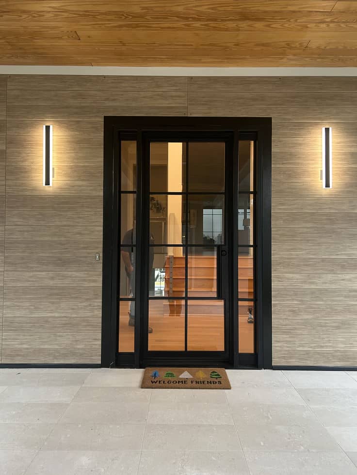 Modern entryway with glass door, welcome mat, and warm lighting. Stylish and inviting home entrance design.