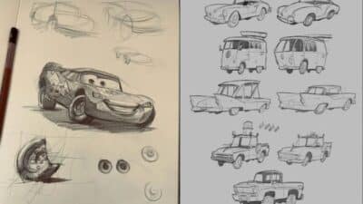 Sketches of animated cars with various designs and expressions on paper, pencil nearby.