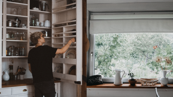 Viewing Deck Blog 4 Person organizing a kitchen cabinet beside a window with a garden view. | Sky Rye Design Person organizing a kitchen cabinet beside a window with a garden view.