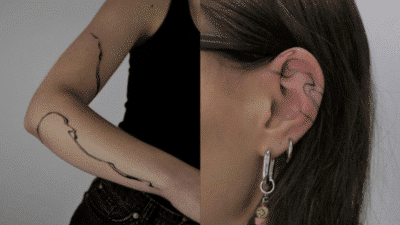 Minimalist line tattoos on arm and ear with elegant abstract designs.