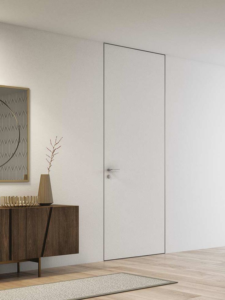 Modern minimalist hallway with a white flush door, wooden cabinet, and decorative mirror.