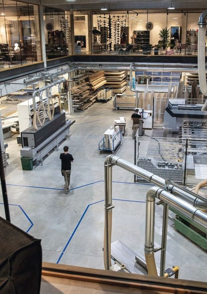 Modern woodworking factory with machinery and workers, viewed from above, showing efficient layout and operations.