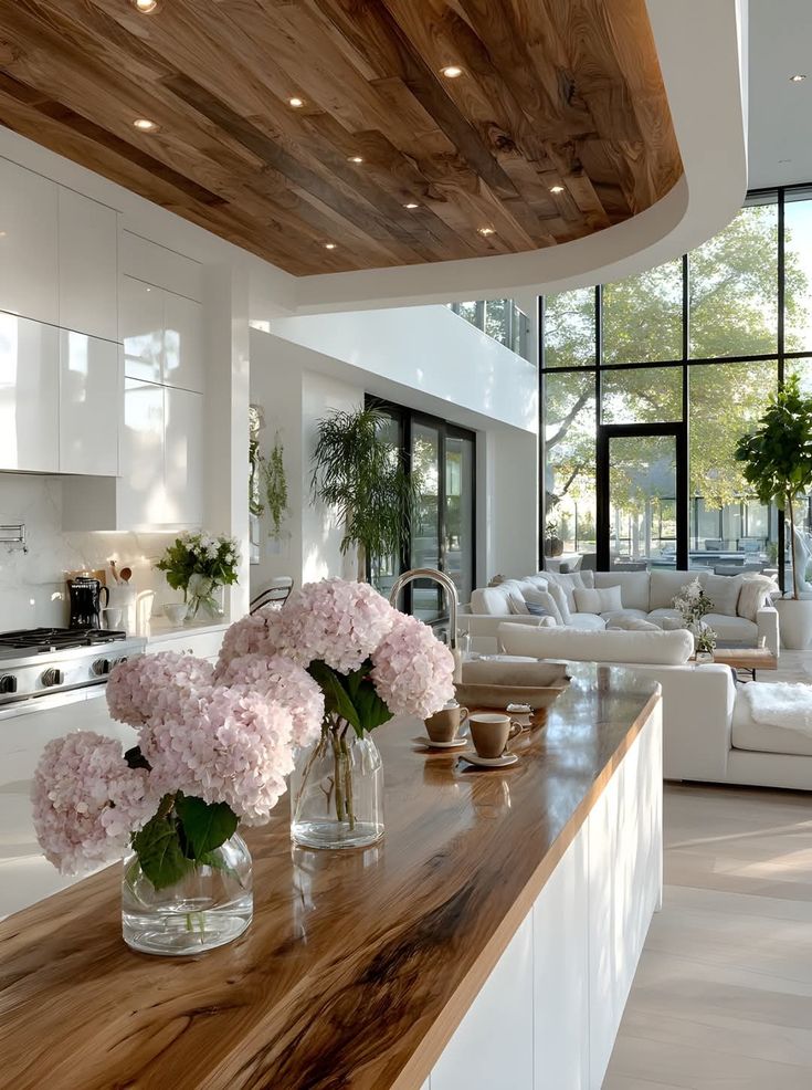 Modern kitchen with wooden accents, large windows, hydrangea flowers, and cozy seating area for a stylish, inviting space.