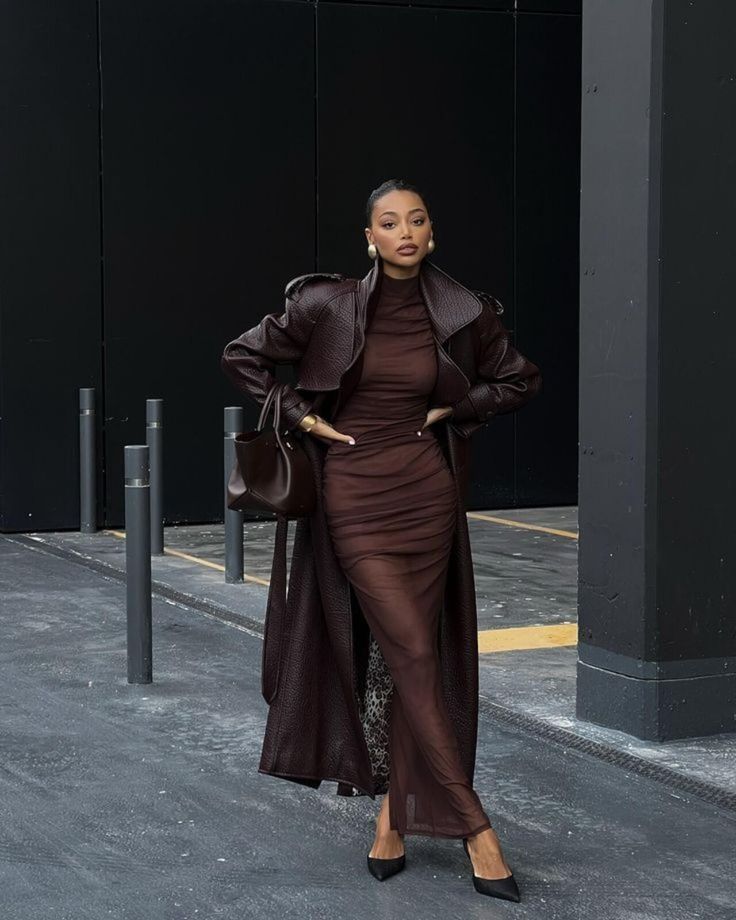 Elegant woman in a stylish brown outfit and trench coat posing confidently in an urban setting.