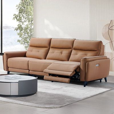 Modern brown leather recliner sofa in a stylish living room with a circular coffee table.