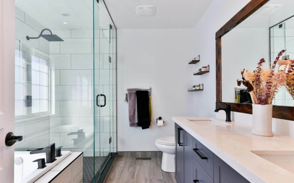 Modern bathroom with glass shower, double sink vanity, and decorative mirror. Elegant interior design.