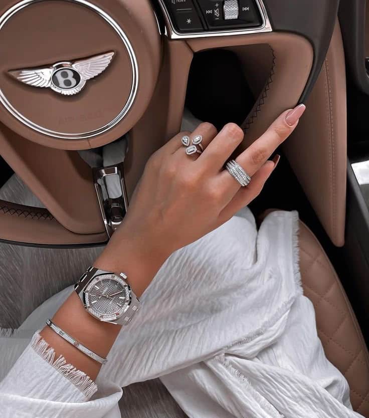 Luxurious wristwatch and rings in a Bentley car, showcasing elegance and style with diamond accessories.