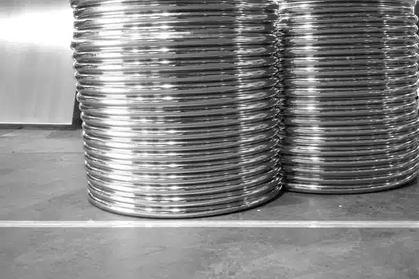 Stacks of shiny metal coils in a warehouse, highlighting industrial materials ready for manufacturing processes.