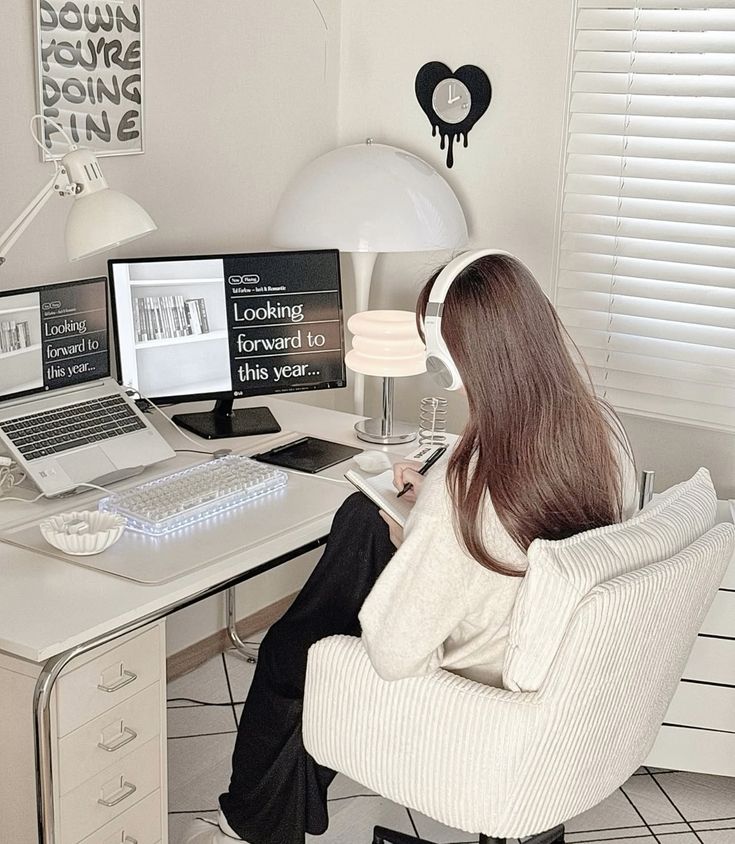 desksetup deskgoals desktopaesthetic Person works at a modern desk setup with a computer and notebook, wearing headphones in a cozy home office. | Sky Rye Design Person works at a modern desk setup with a computer and notebook, wearing headphones in a cozy home office.