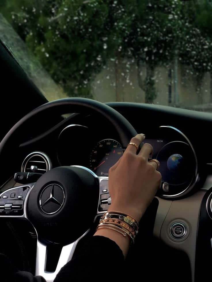 dhndhd Hand with bracelets on a Mercedes steering wheel on a rainy day, emphasizing luxury driving experience. | Sky Rye Design Hand with bracelets on a Mercedes steering wheel on a rainy day, emphasizing luxury driving experience.