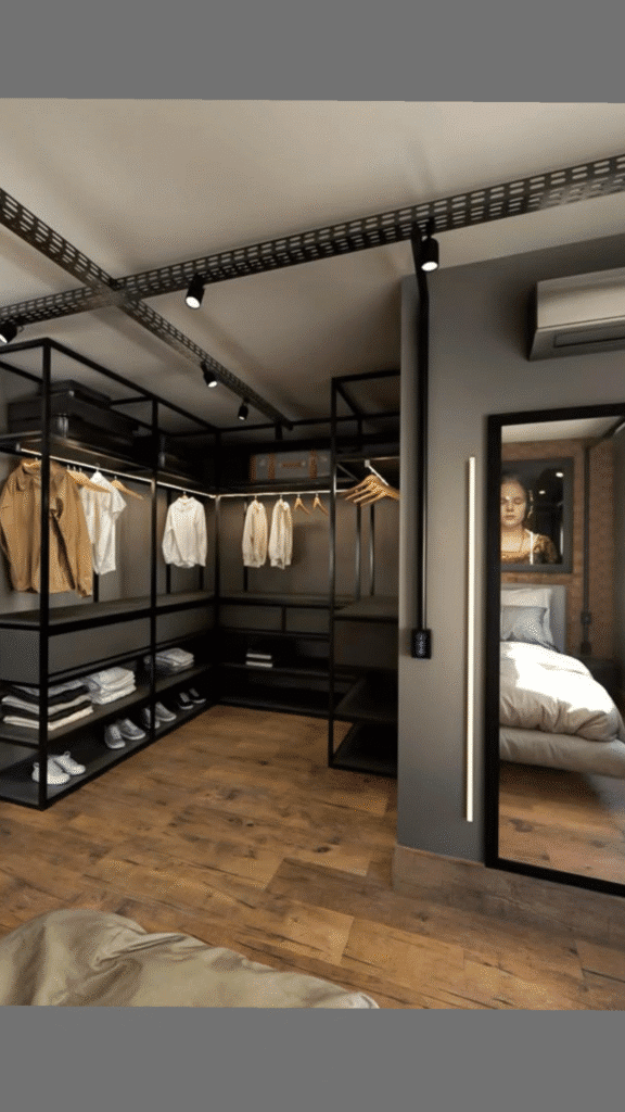 Modern walk-in closet with clothes on hangers, shelves, and a mirror reflecting a bedroom.