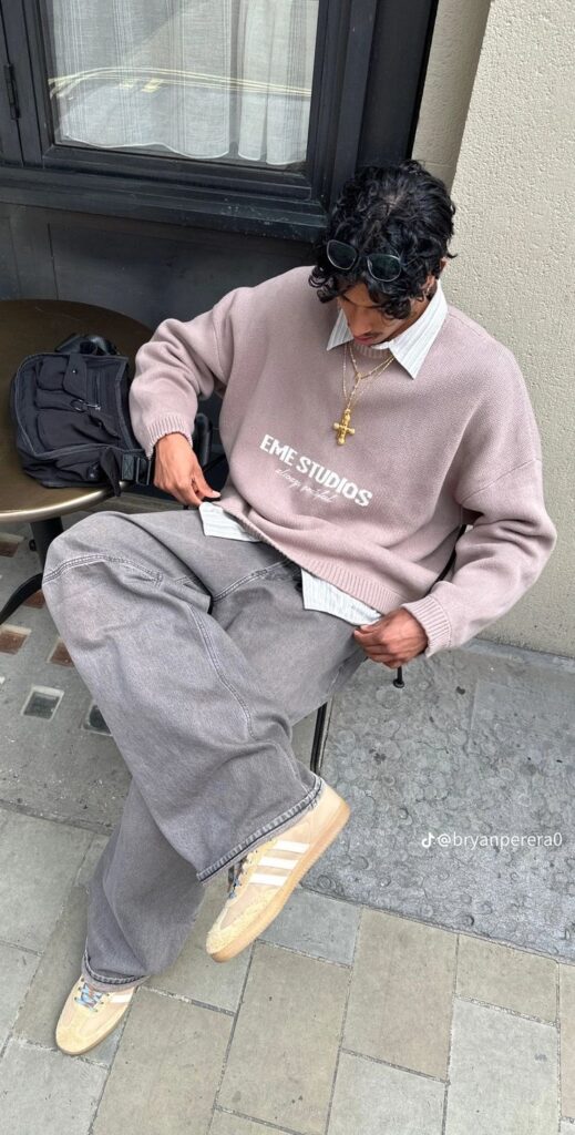Street style outfit with EME Studios sweater, gray jeans, sneakers, and accessories. Urban fashion look.